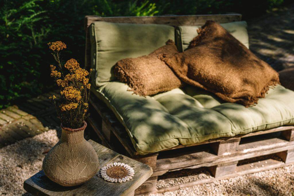 Alt Tag: Bruine kussenhoes van zacht katoen op groene tuinbank, ontworpen voor een boho-touch in uw inrichting zonder binnenkussen.