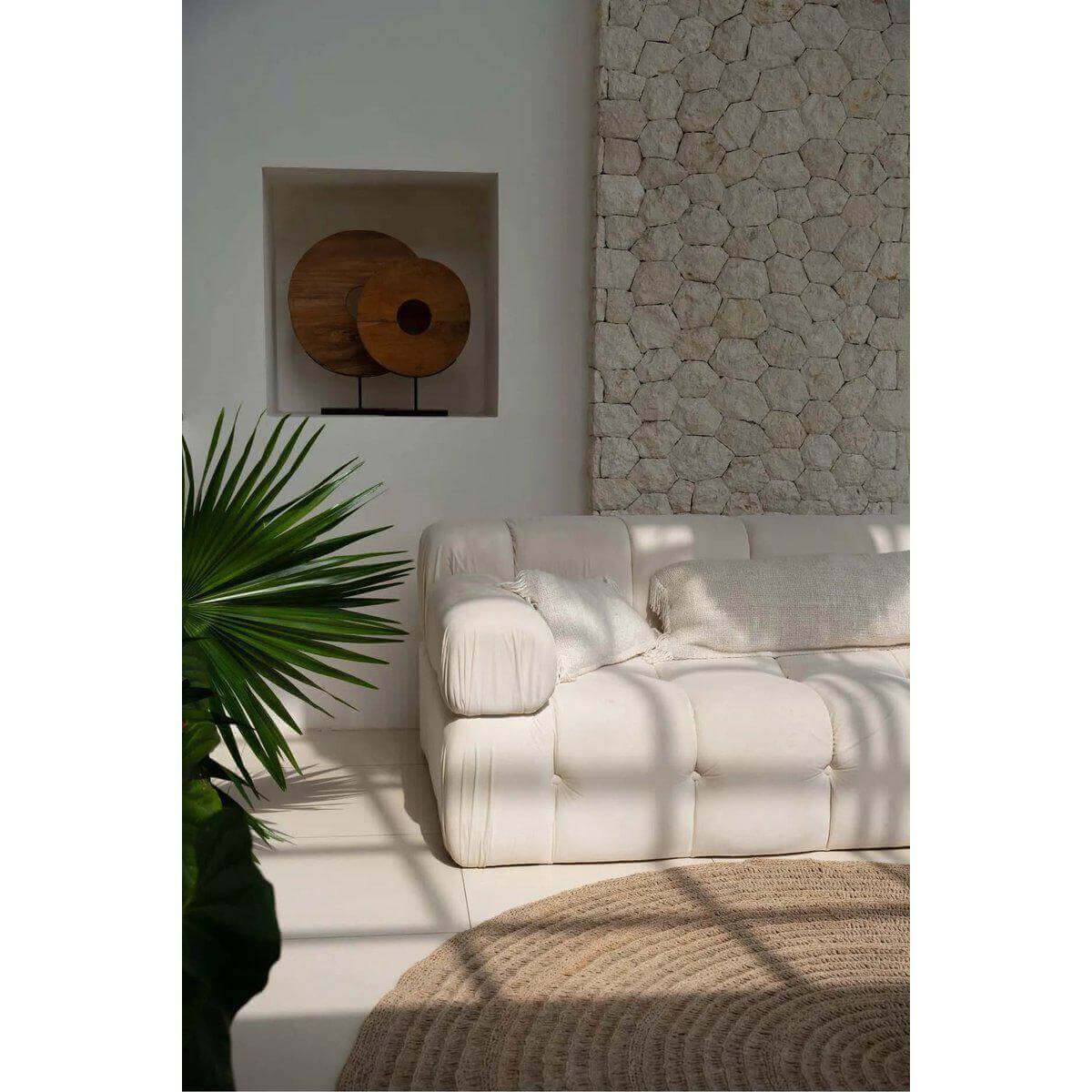 Witte katoenen kussenhoes 40x40 op een boho bank, tegen een rustieke stenen muur, voor een sfeervolle woonkamer.