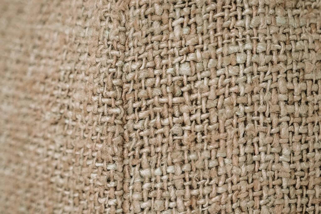 Gedetailleerde close-up van de textuur van een beige katoenen stof, perfect voor een stijlvolle en comfortabele woonaccessoire.