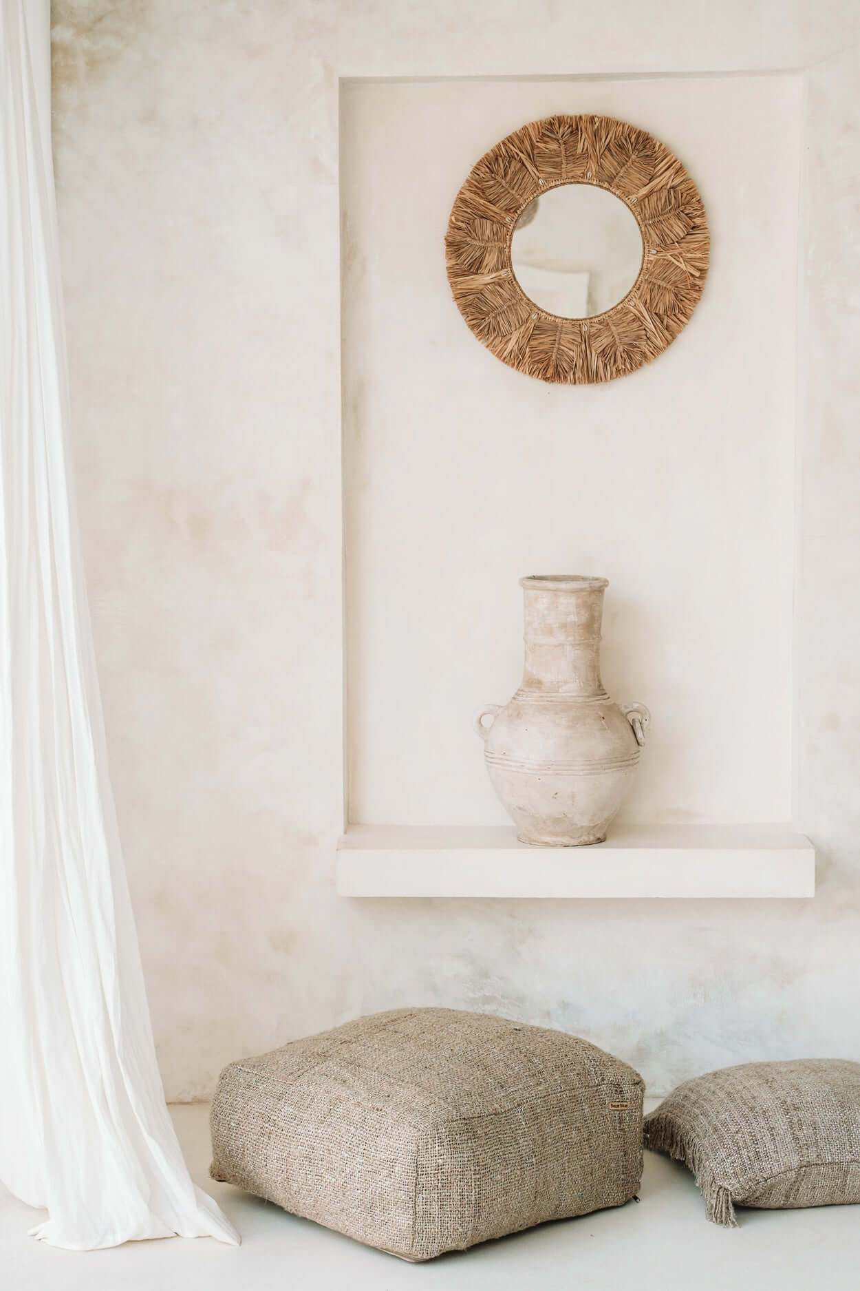 Beige katoenen poef in stijlvolle minimalistische woonkamer met vaas en spiegel, ideaal als decoratief en functioneel zitelement.