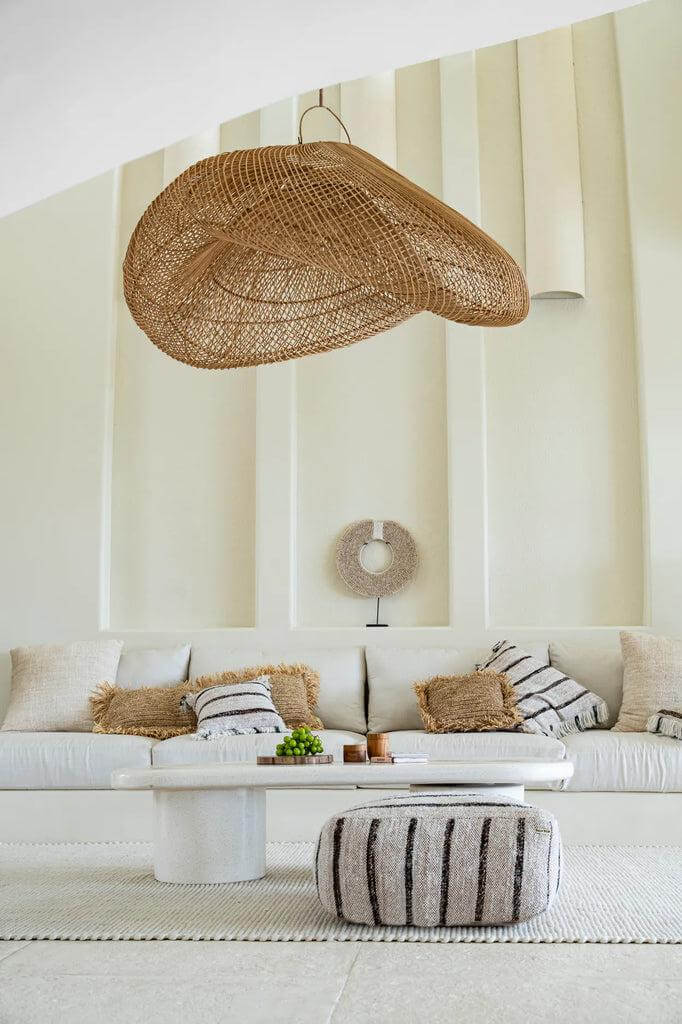 Gezellige woonkamer met bohemian inrichting, inclusief katoenen poef en natuurlijke hanglamp; perfect voor stijlvol ontspannen.