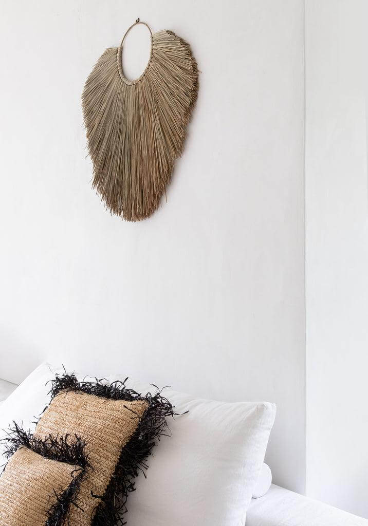 De Raffia Kussenhoes in naturel zwart op witte bank, met handgeweven textuur en boho uitstraling, 60x60 cm, zonder binnenkussen.