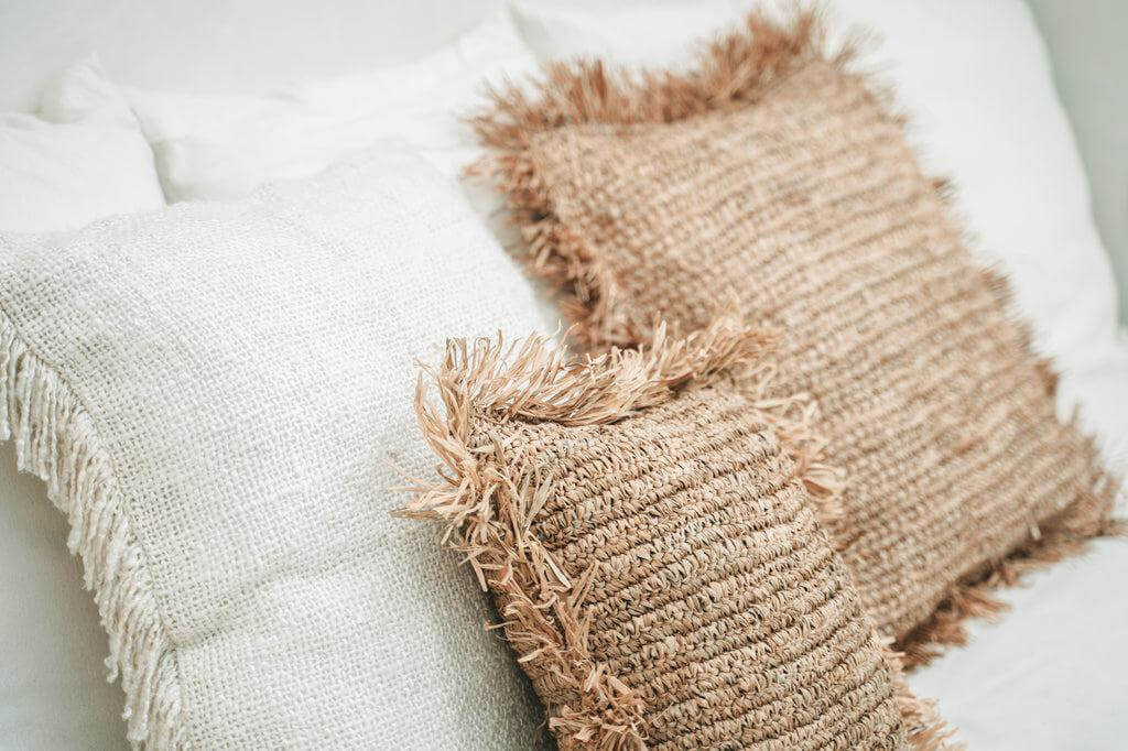 Stijlvolle vierkante raffia kussenhoes in natuurlijke tinten, handgeweven in Indonesië, perfect voor boho-sfeer in huis of tuin.