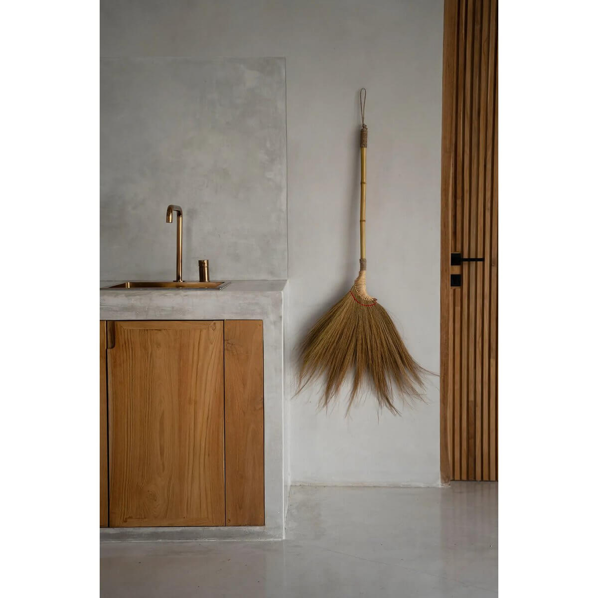 Bohemian style Indonesian broom, handmade from natural fibers, hanging decoratively in a modern interior space.