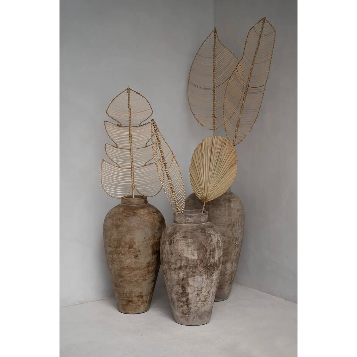 Three elegant clay vases with Bohemian-style rotan leaf decor by Bazar Bizar Living, enhancing natural charm in a modern interior space.