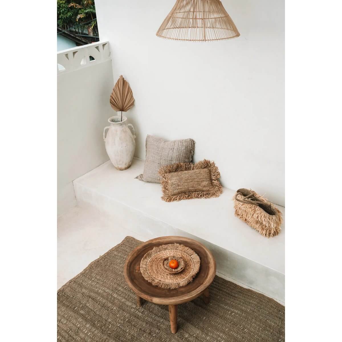 Cozy bohemian interior with seagrass placemat, raffia decor, cushions, and woven accents for a tropical vibe.