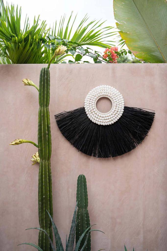 Zwart alang alang wandkunstwerk met schelpen, decoratie op buitenmuur met cactussen, natuurlijke texturen en exotische uitstraling.