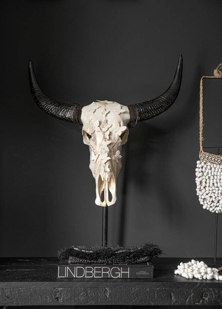 Alt Tag: Decoratieve schedel op standaard met donkere hoorns, naast handgemaakte witte schelpen tas, bohemian chic interieur.