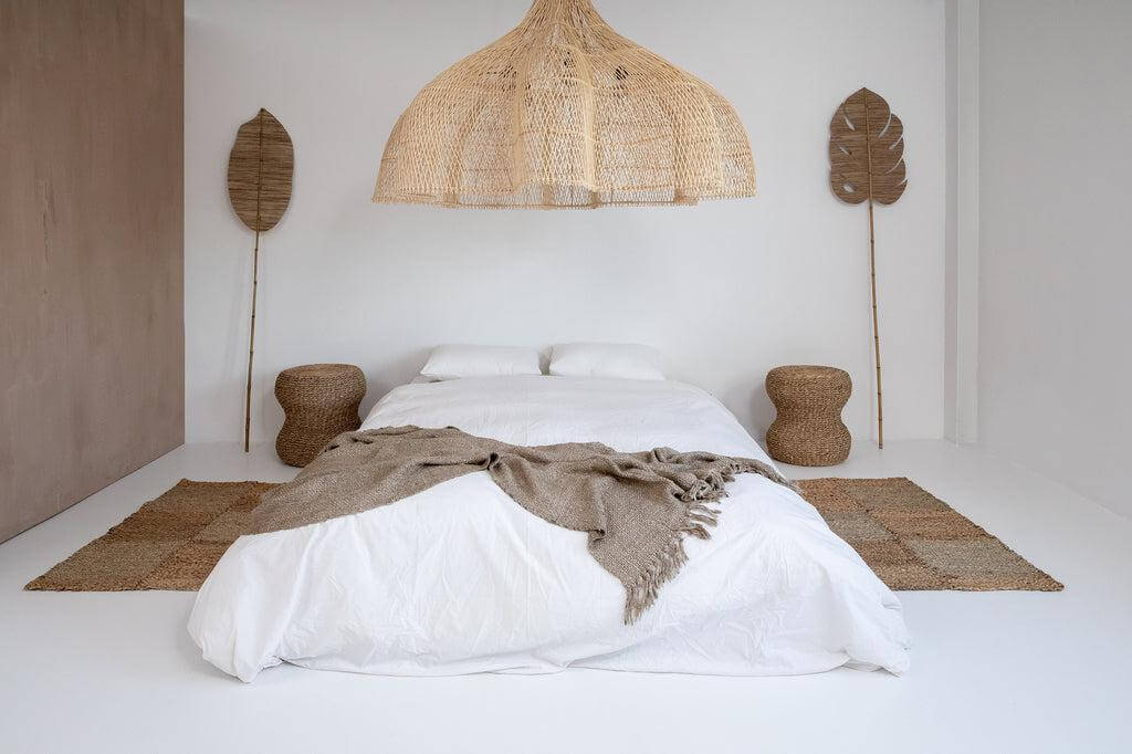 Stijlvolle slaapkamer met een luxe handgeweven beige plaid op het bed, omgeven door natuurlijke decoraties.