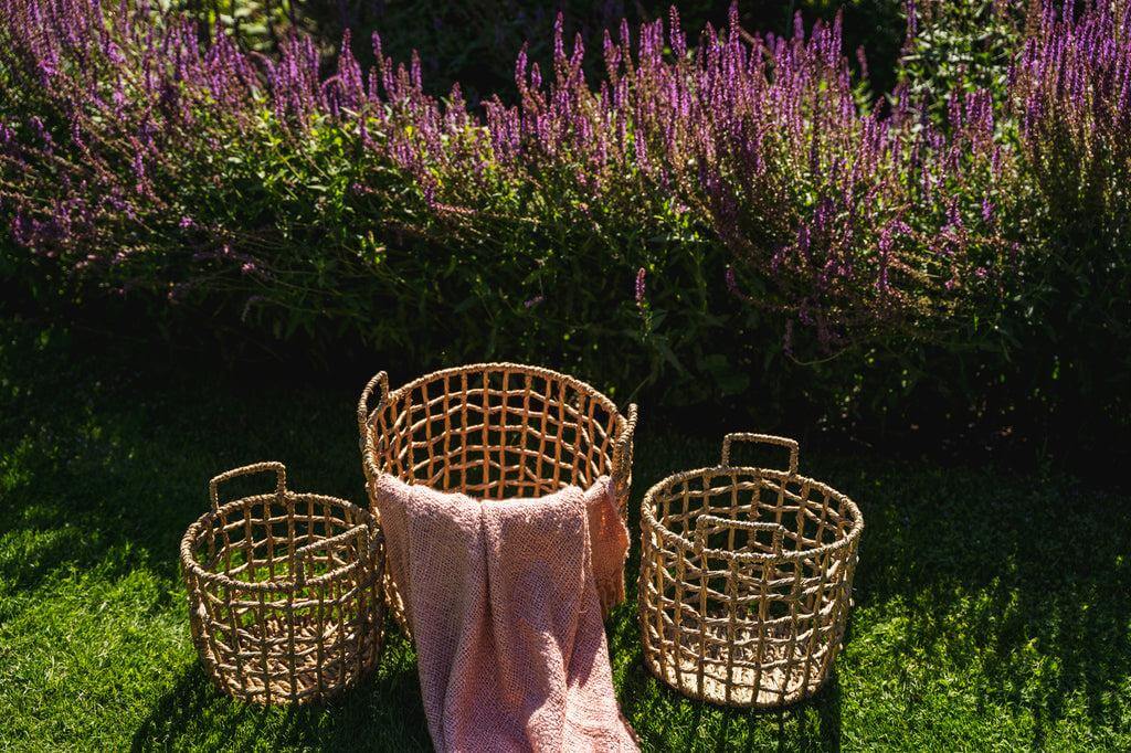 Zalm roze katoenen plaid met franjes tussen rieten manden in bloementuin