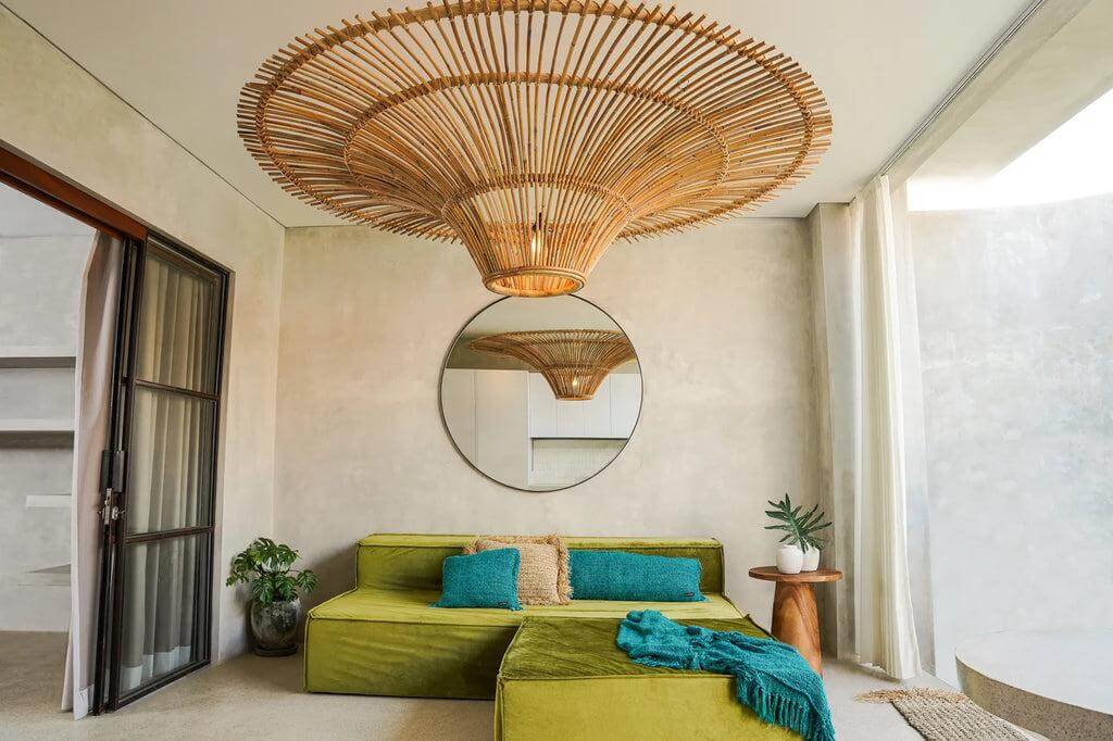 Prachtige rotan De Sky Hanglamp XXL in natuurlijke kleur, centraal boven modern interieur met groene bank en ronde spiegel.