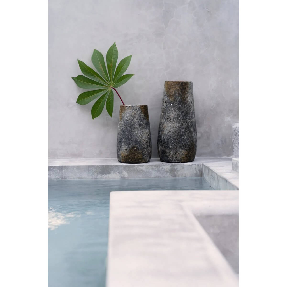Bohemian-style Spooky terracotta vases in antique grey near a pool, featuring leafy decor. Perfect for dried or fresh blooms.