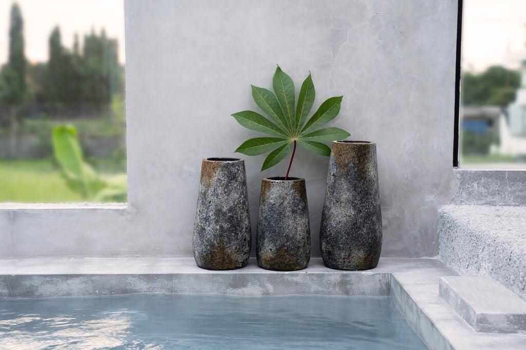 Drie antieke grijze Spooky vazen met plant naast zwembad, elegantie in terracotta met zilverachtige glans.