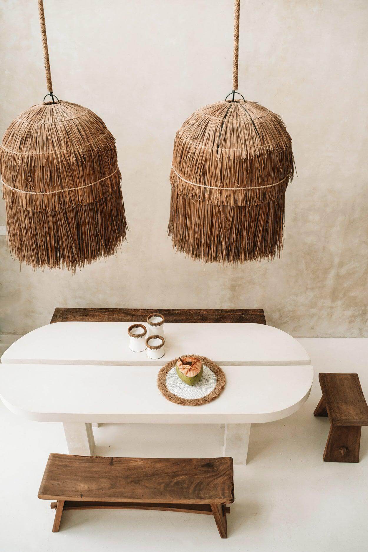 Suar hout bank bij een witte tafel met rieten hanglampen, perfecte natuurlijke elegantie voor elk interieur.