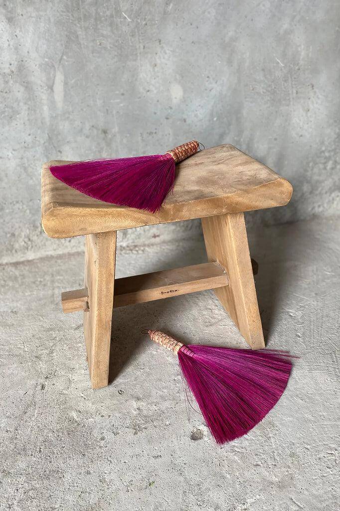 Compacte De Suar kruk van hout met twee paarse bezems, veelzijdig voor huisgebruik, perfect voor handdoeken of kleding.