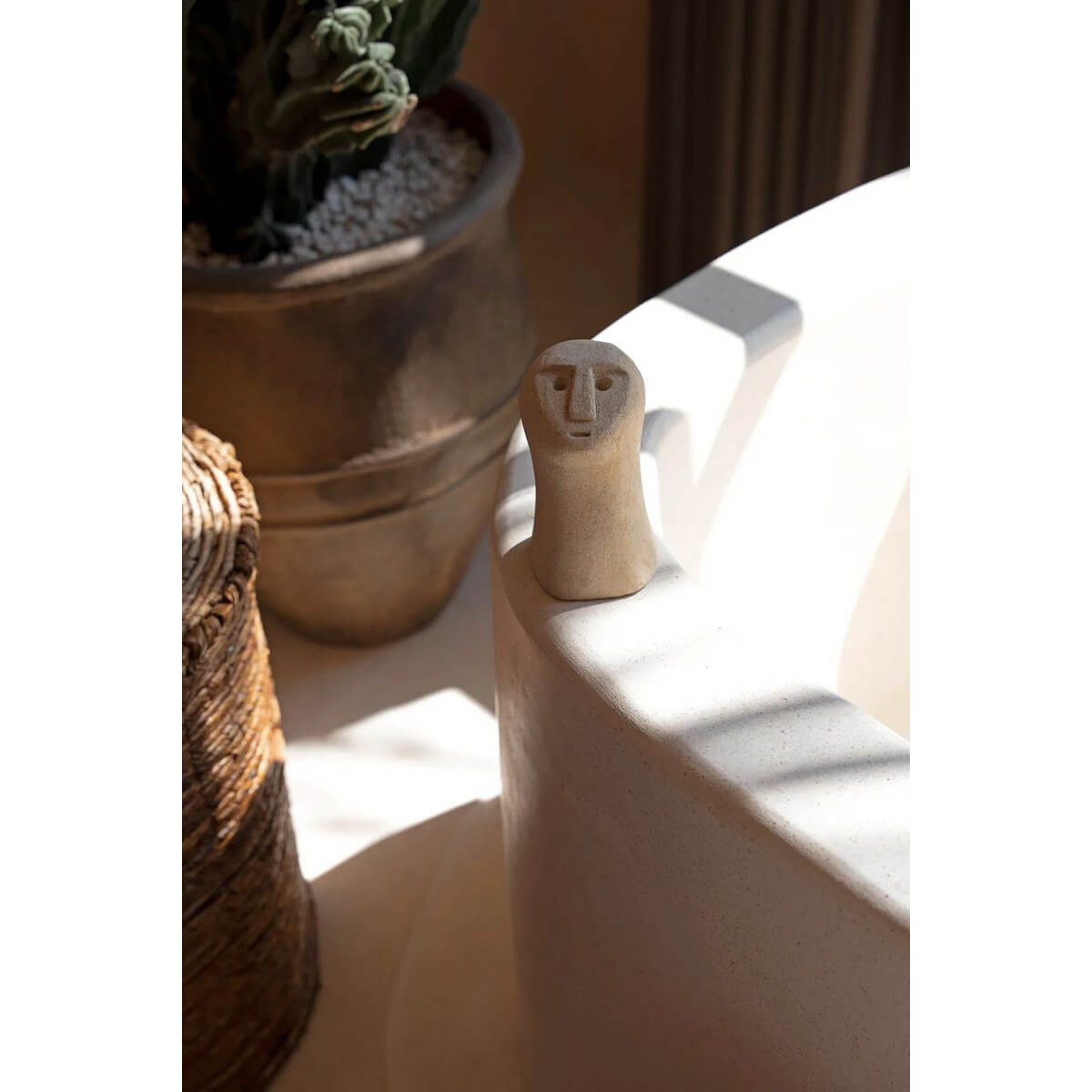 Bohemian Sumba stone statue on a bath edge, handmade from sandstone by Indonesian artisans, adding a protective and healing presence.