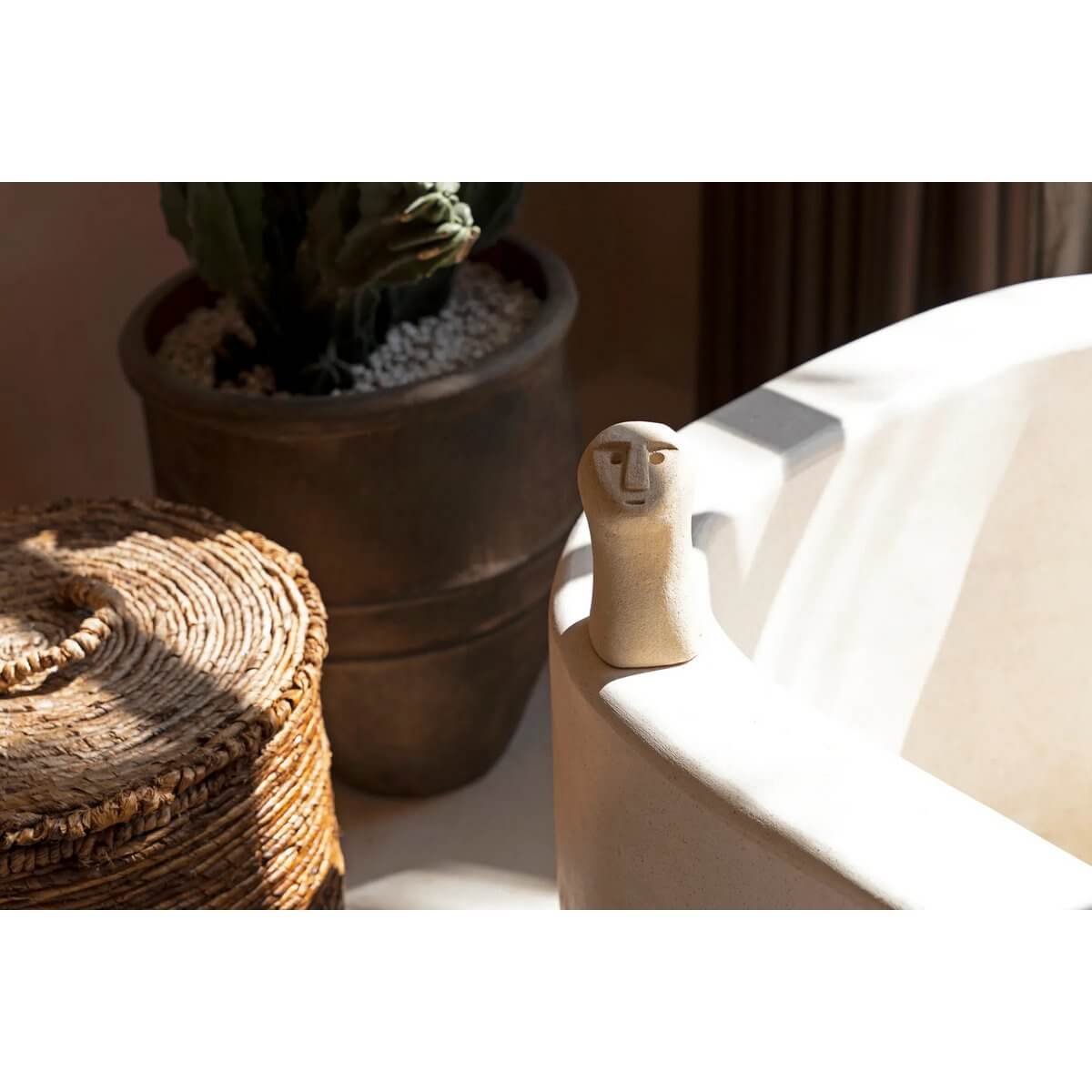 Bohemian sandstone statue from Sumba, Indonesia, seated on a ledge in warm light, showcasing artisan craftsmanship for decor and protection.