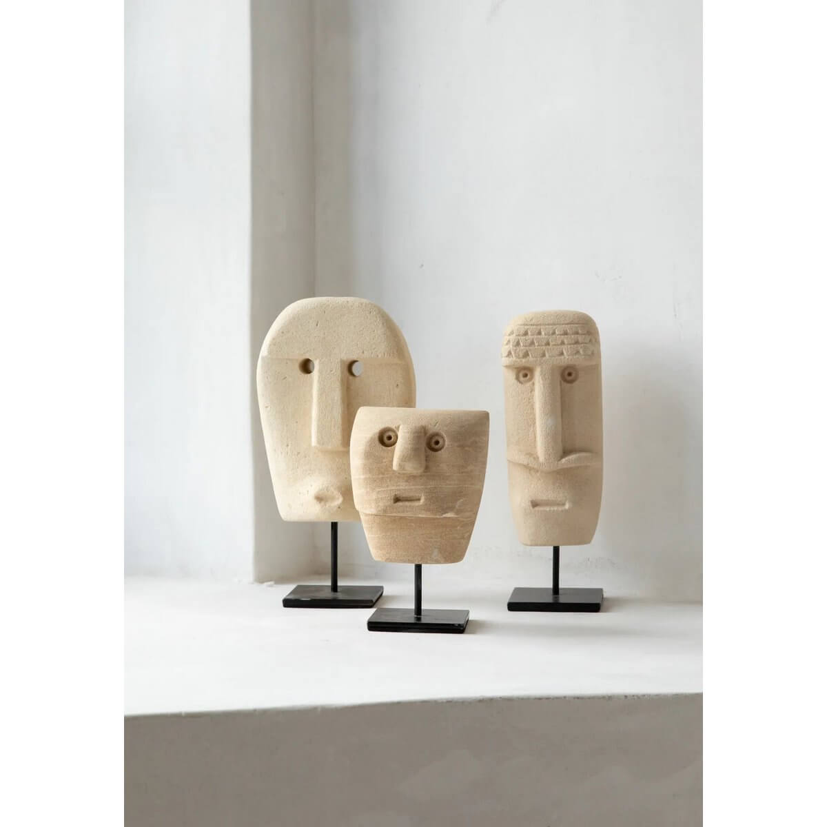 Three hand-carved Sumba stone sculptures on stands, capturing a bohemian vibe with their unique sandstone style, crafted in Indonesia.