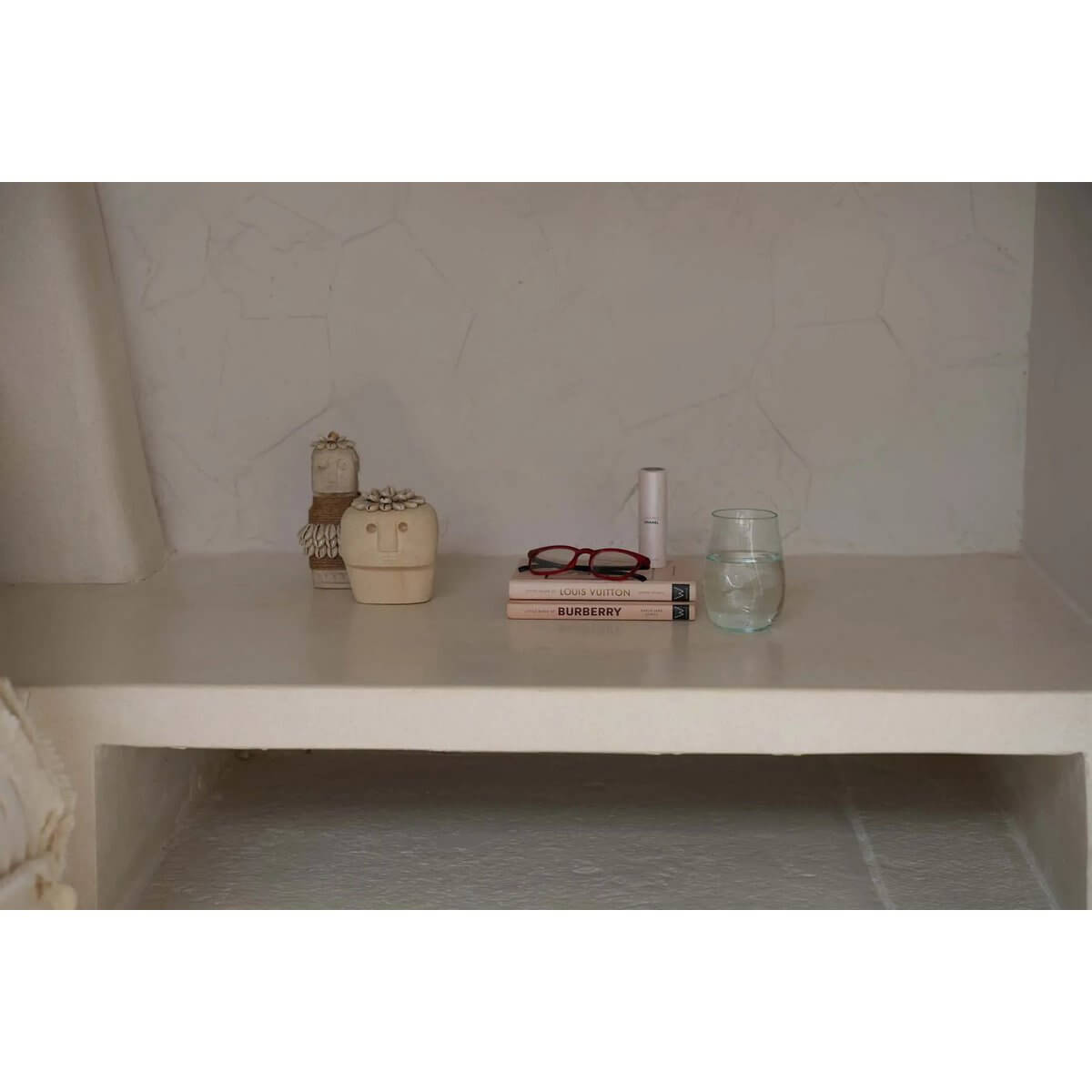 Two Sumba stones on shelf with books, glasses, and a glass vase for a bohemian decor vibe.