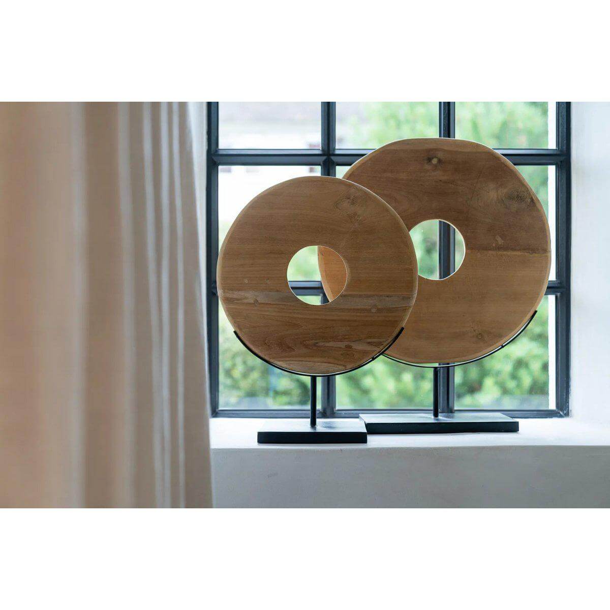 Alt Tag: Decoratieve teakhouten schijf op standaard bij raam, mooi voor interieurdecoratie en overdekte terrassen.