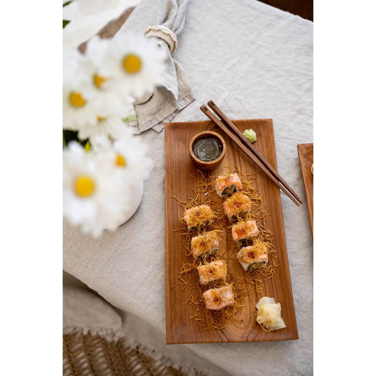 Stylish sushi platter with chopsticks and soy sauce on a wooden board, embracing a bohemian dining aesthetic for elegant presentations.
