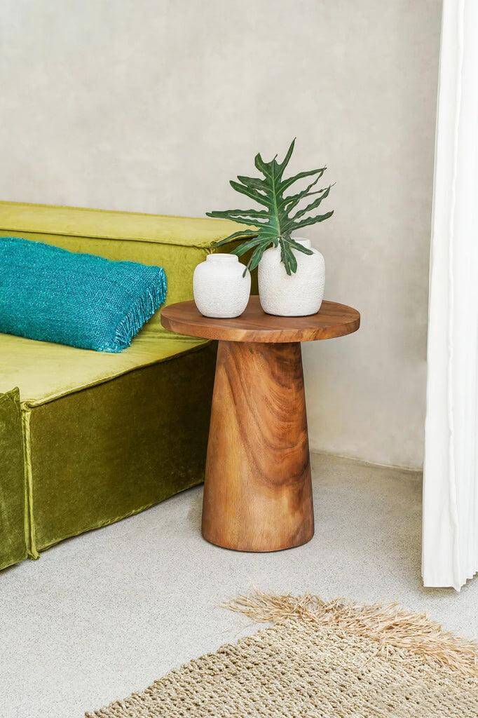 Houten conische bijzettafel naast groene bank, versierd met plantenpotten, handgemaakt van Munggur hout, unieke scheuren en markeringen.