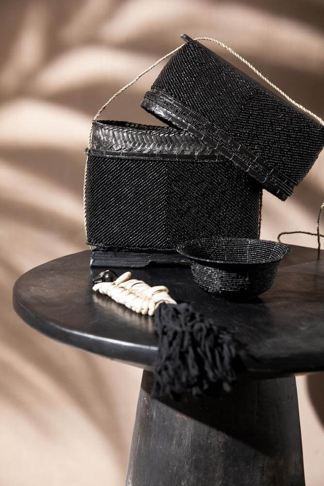 Stijlvolle zwarte Timber Conic bijzettafel van Munggur hout met artistiek opgestelde handgemaakte manden en accessoires.
