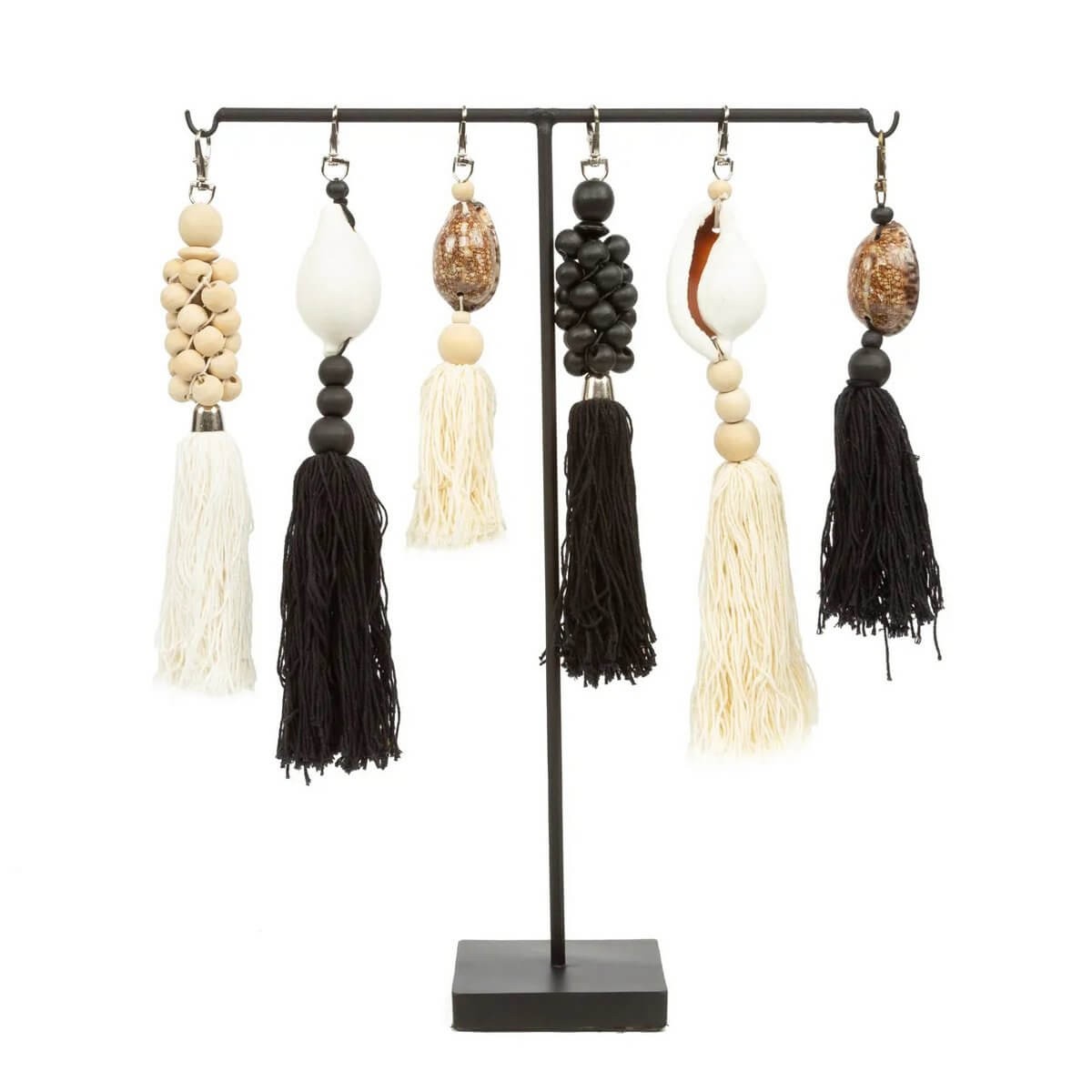 Bohemian style keychains with natural white beads, tassels, and shells on a display stand.