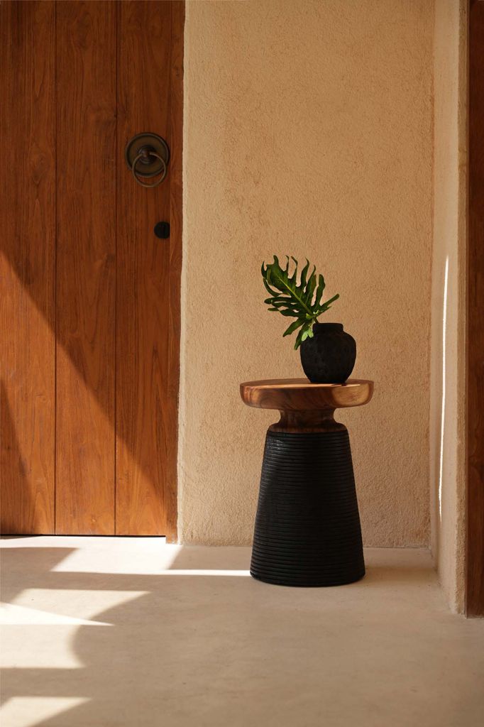 Zwarte trendy vaas op houten tafel in zonnige ruimte, perfect voor gedroogde bloemen. Hoogte 14 cm, opvallend eigentijds design.
