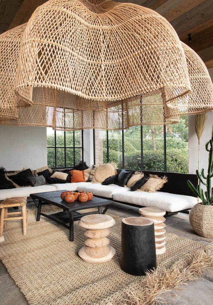 Stijlvolle woonkamer met gevlochten hanglamp, zwarte bank, en De Tribe Kruk - Naturel Zwart in een modern interieur.