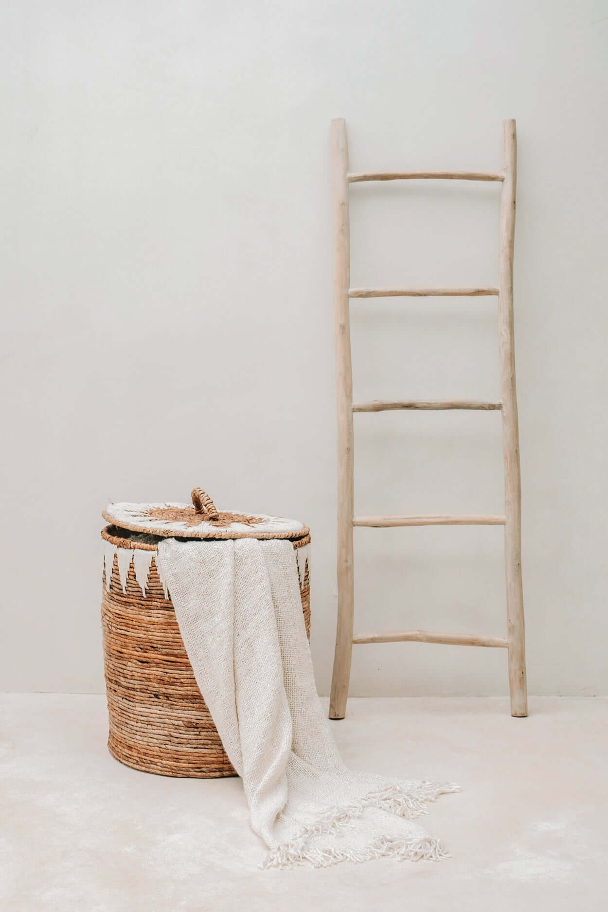 Natuurlijke teakhouten boho ladder naast mand in lichte kamer, perfecte decoratieve blikvanger voor handdoeken en plaids in huis.