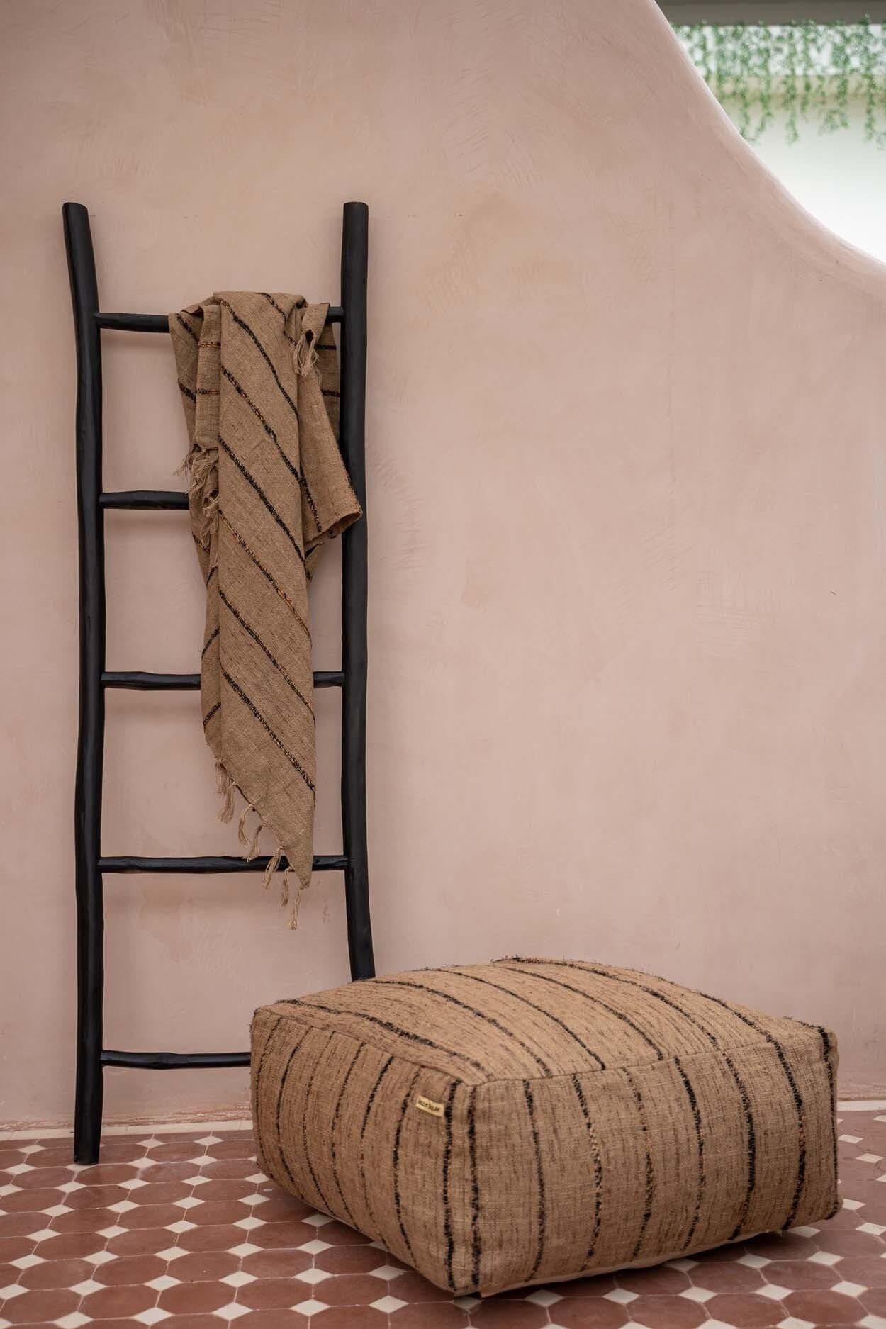 Zwarte teakhouten boho ladder met plaid in moderne ruimte. Decoratieve blikvanger voor badkamer, woonkamer en buiten.