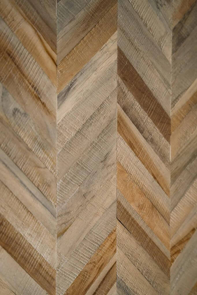 Close-up van visgraatpatroon in teakhout, elegant en naturel, perfect voor meubels zoals banken en tafels.
