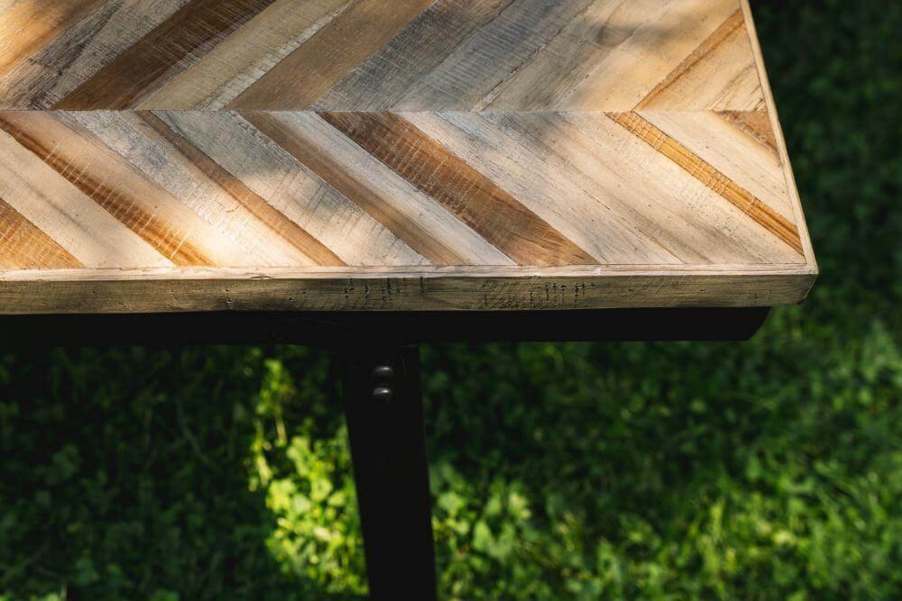 Visgraat tafelblad van teakhout met zwart ijzeren onderstel, perfect voor binnen en buiten gebruik als eettafel. Inklapbaar en stijlvol.