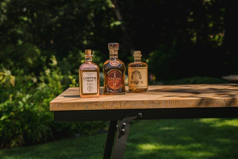 Elegant teakhouten visgraat console met flessen drank op een zonnige dag in de tuin. Perfect als eettafel binnen of buiten.