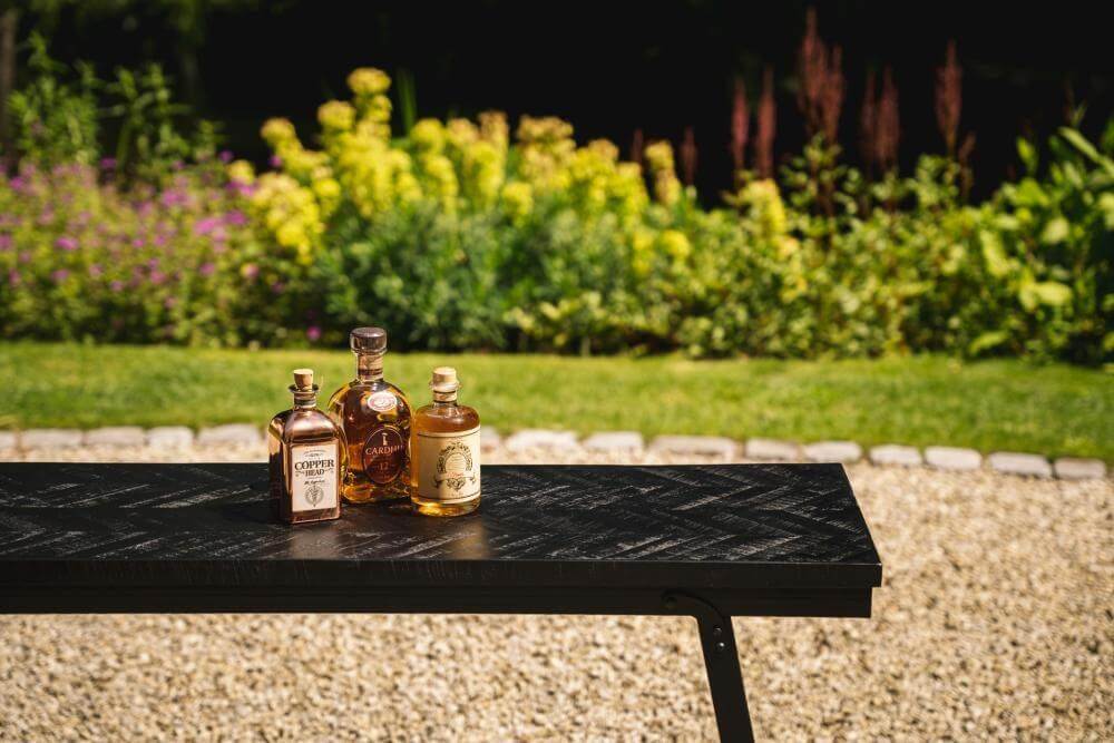 Zwarte visgraat tafel met flessen drank buiten bij kleurrijke tuin