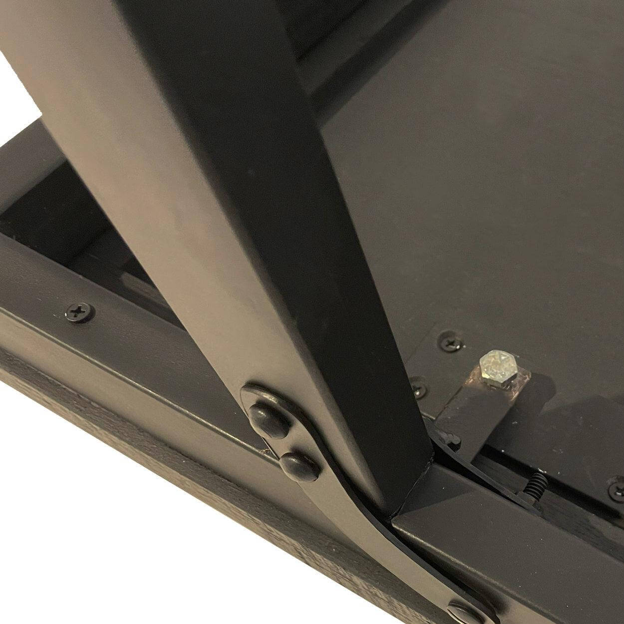 Close-up van het inklapmechanisme van de zwarte visgraat tafel, gemaakt van teakhout en ijzer, voor binnen en overdekt buiten gebruik.