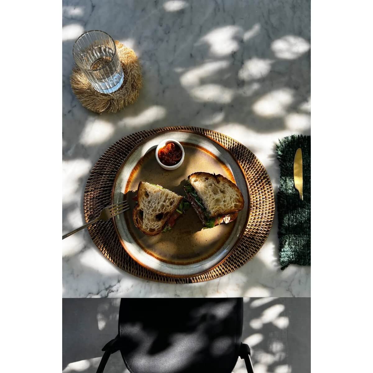 Bohemian rotan placemat in natural brown with gourmet sandwich and dipping sauce, enhancing a tropical dining experience.