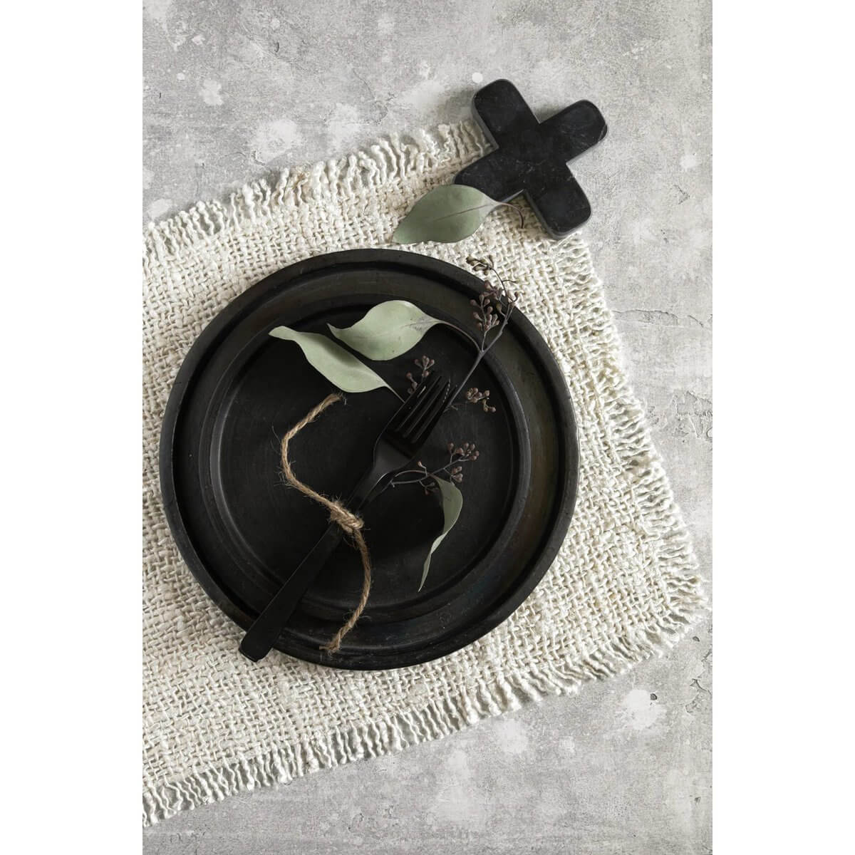 Elegant black marble trivet by Bazar Bizar Living, featuring a bohemian touch, placed on woven cloth with eco-friendly tableware.