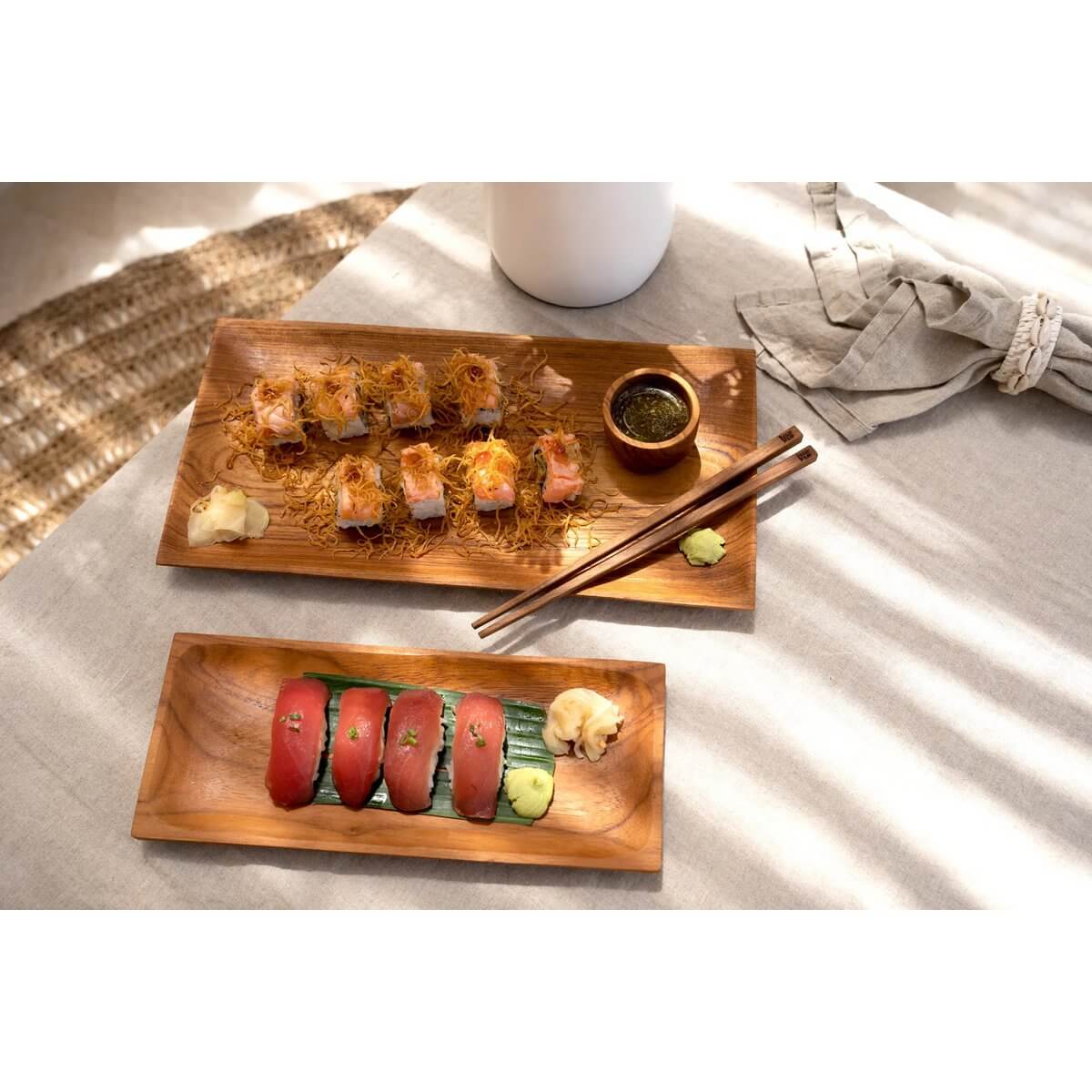 Bohemian teak root chopsticks on elegant wooden plates with sushi, adding sustainable style to a dining setting.