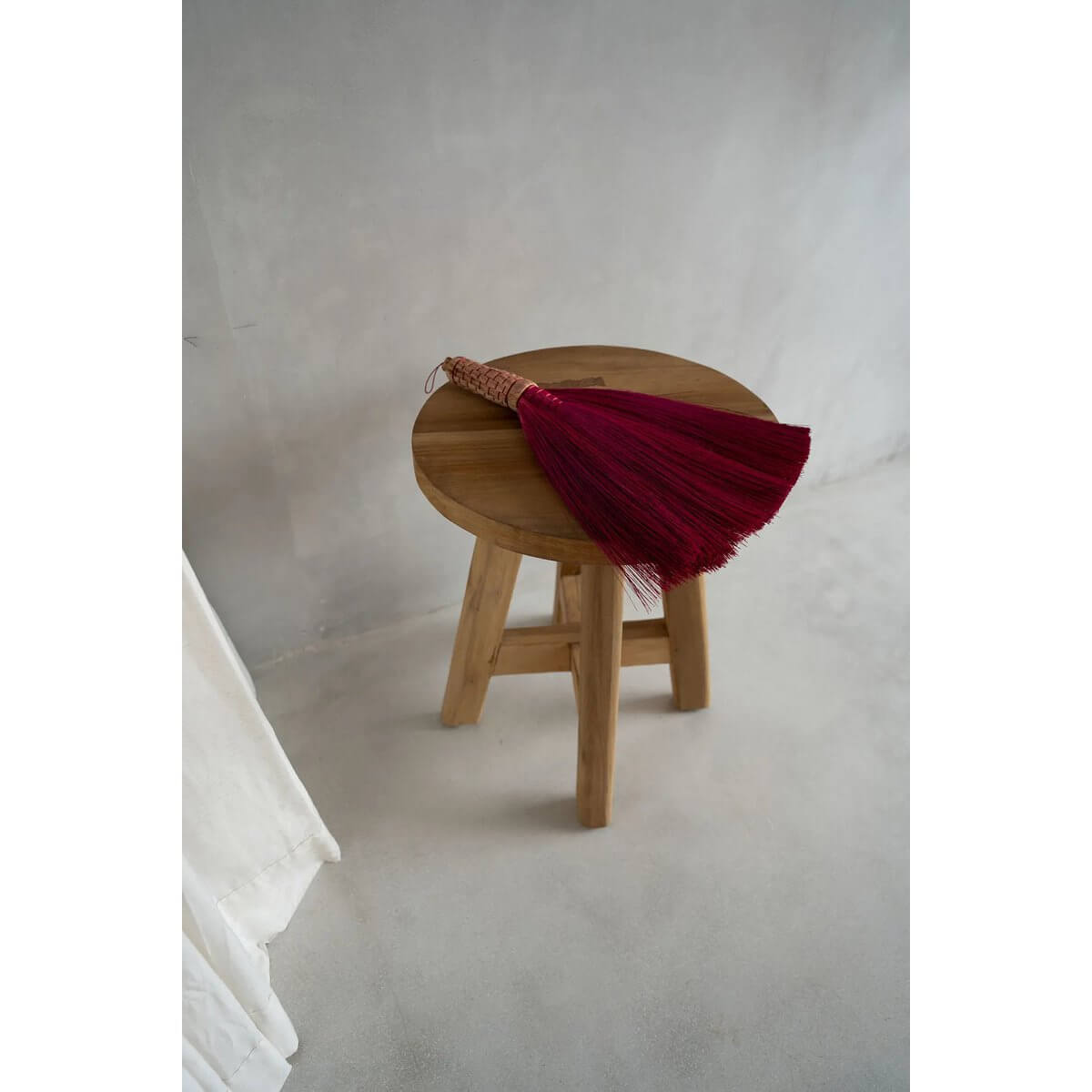 Handcrafted Indonesian pink grass broom on wooden stool, perfect for a Bohemian décor, effortlessly sweeps dirt and dust away.