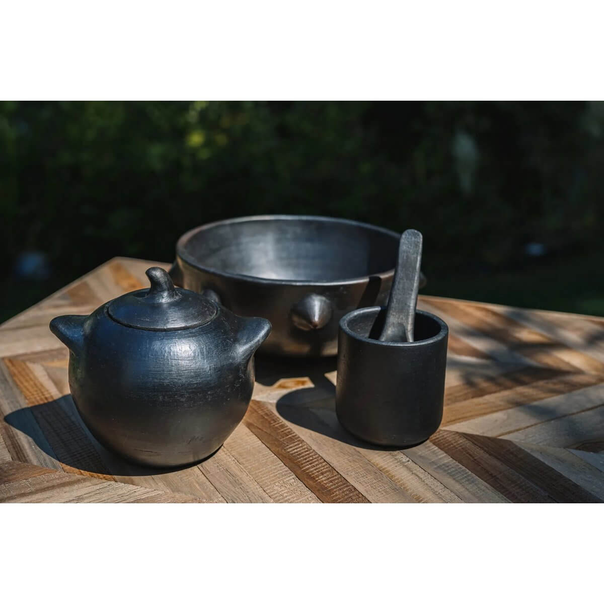 Alt Tag: Zwartgeblakerd servies uit de Burned-collectie, inclusief een unieke pot met deksel en stijlvol lepeltje, perfect voor kleurrijke maaltijden.