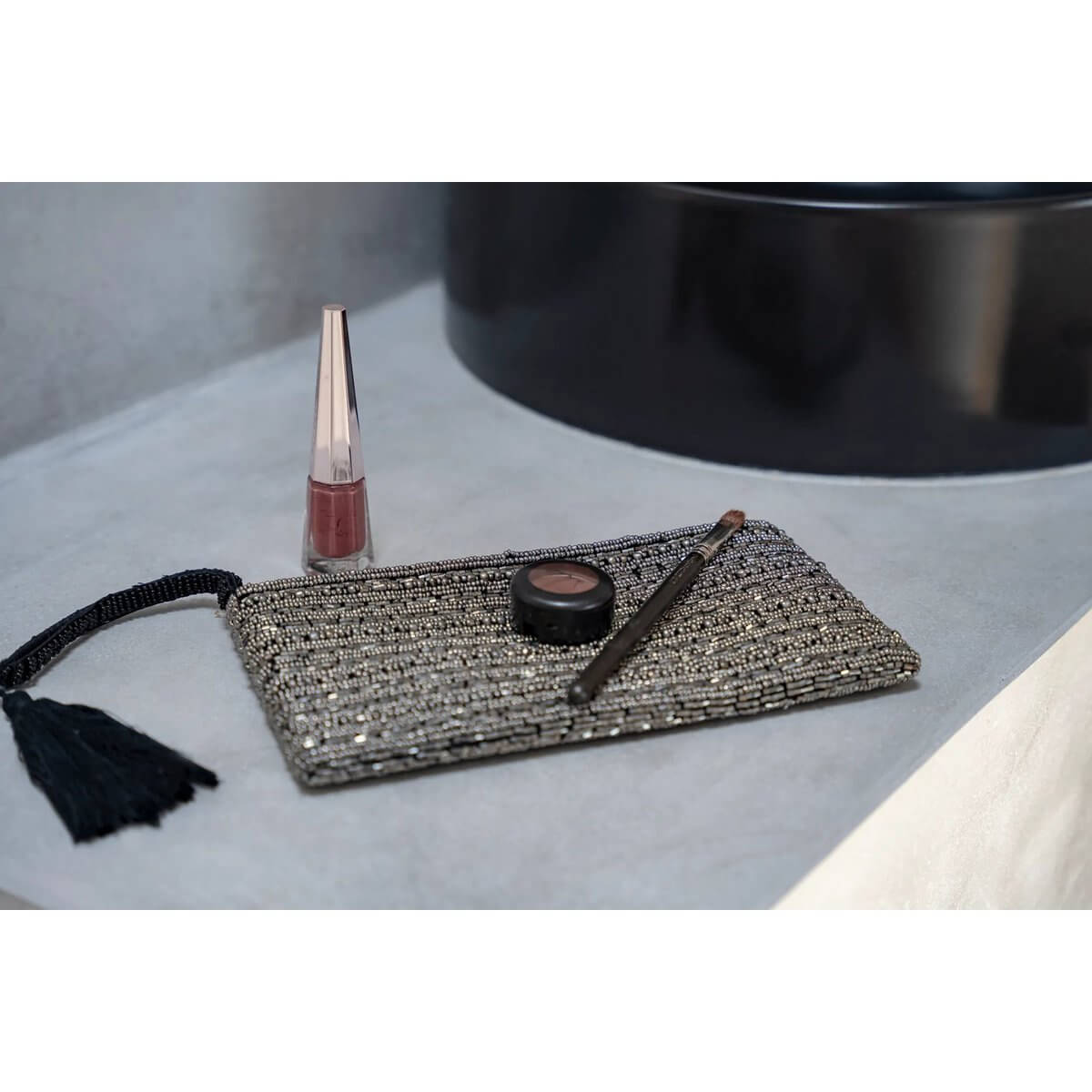 Bohemian silver clutch on display with lip gloss and eyeliner, perfect for carrying essentials in style.