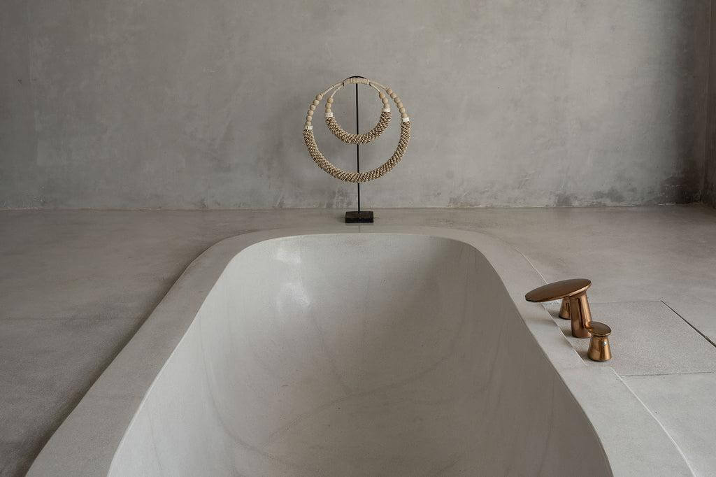 Dubbele halsketting met schelpen op standaard in minimalistische badkamerdecoratie.