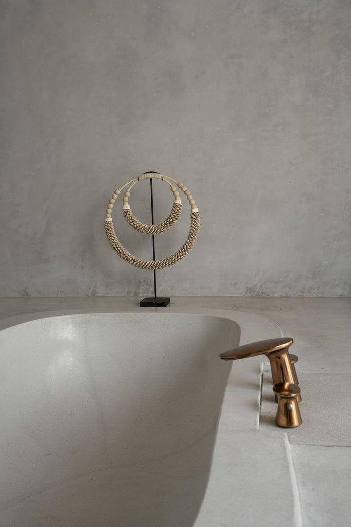 Dubbele halsketting met schelpen op standaard in badkamer, Balinese stijl decoratie, natuurlijke kleuren.