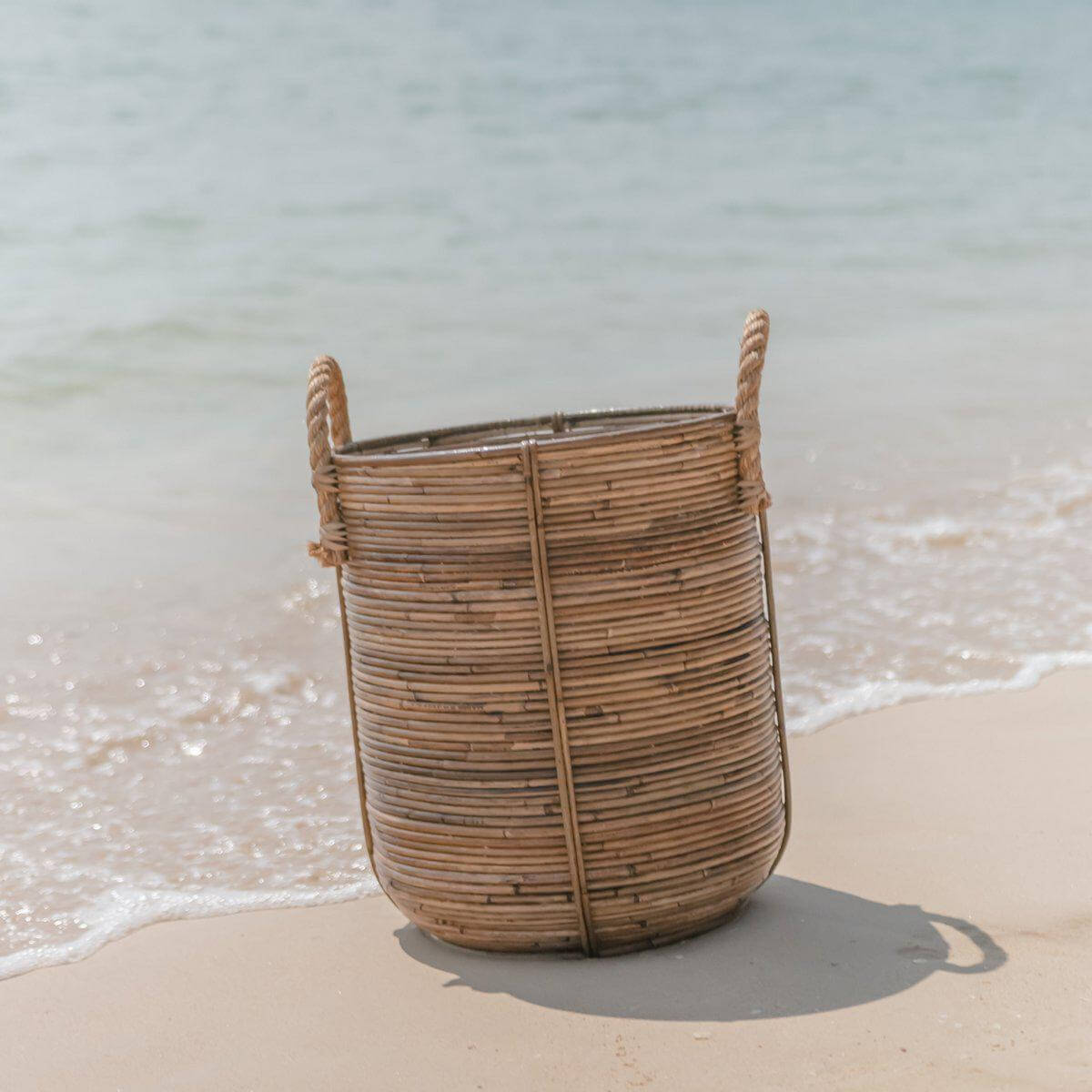 Boho rotan wasmand Otere op strand, tropische charme voor huisorganisatie