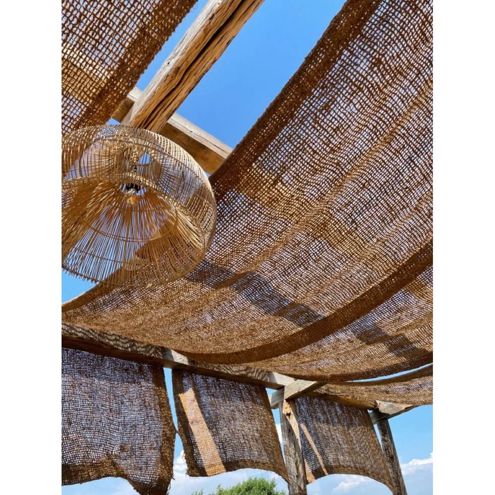 Rustic Coco Fence made of coconut fiber, adding Bohemian charm to a garden setting under a bright blue sky.