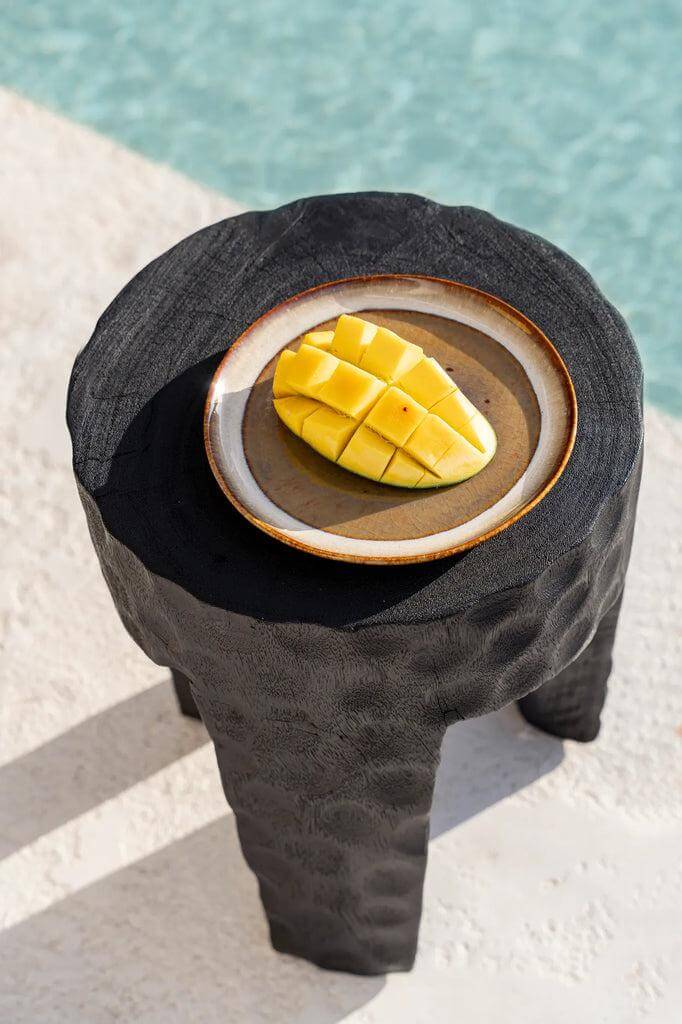 Een Comporta bord met gesneden mango op een stijlvol zwart bijzettafeltje bij het zwembad. Perfect voor brunch of diner.