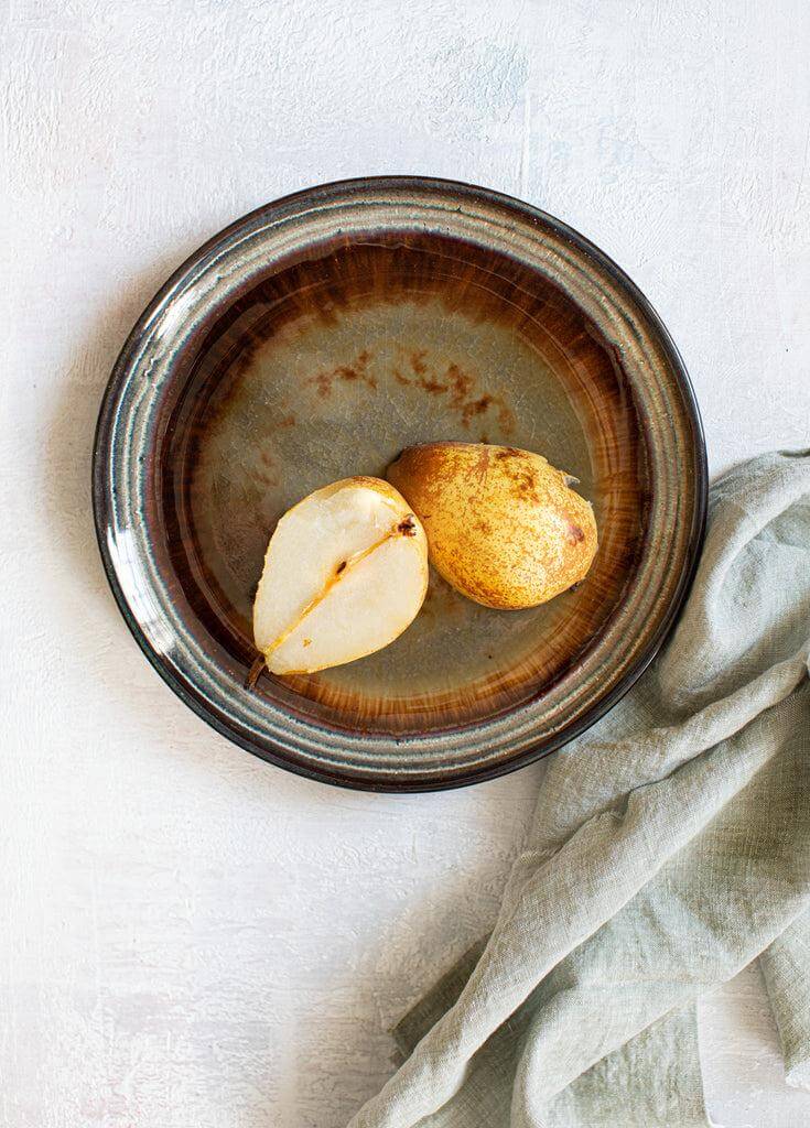 "Het Comporta Bord M met craquelé glazuur en halve peer, perfect voor elke brunch of diner."