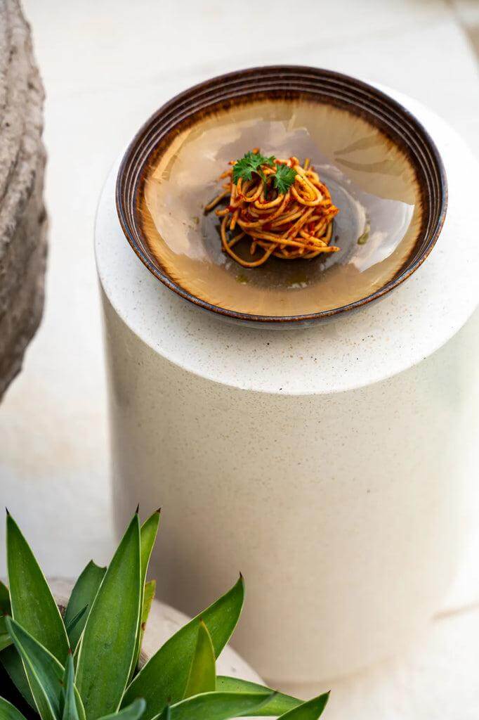 Het Comporta Pastabord met pasta en groene kruiden op een elegante sokkel, uit de Portugese keramiek collectie.